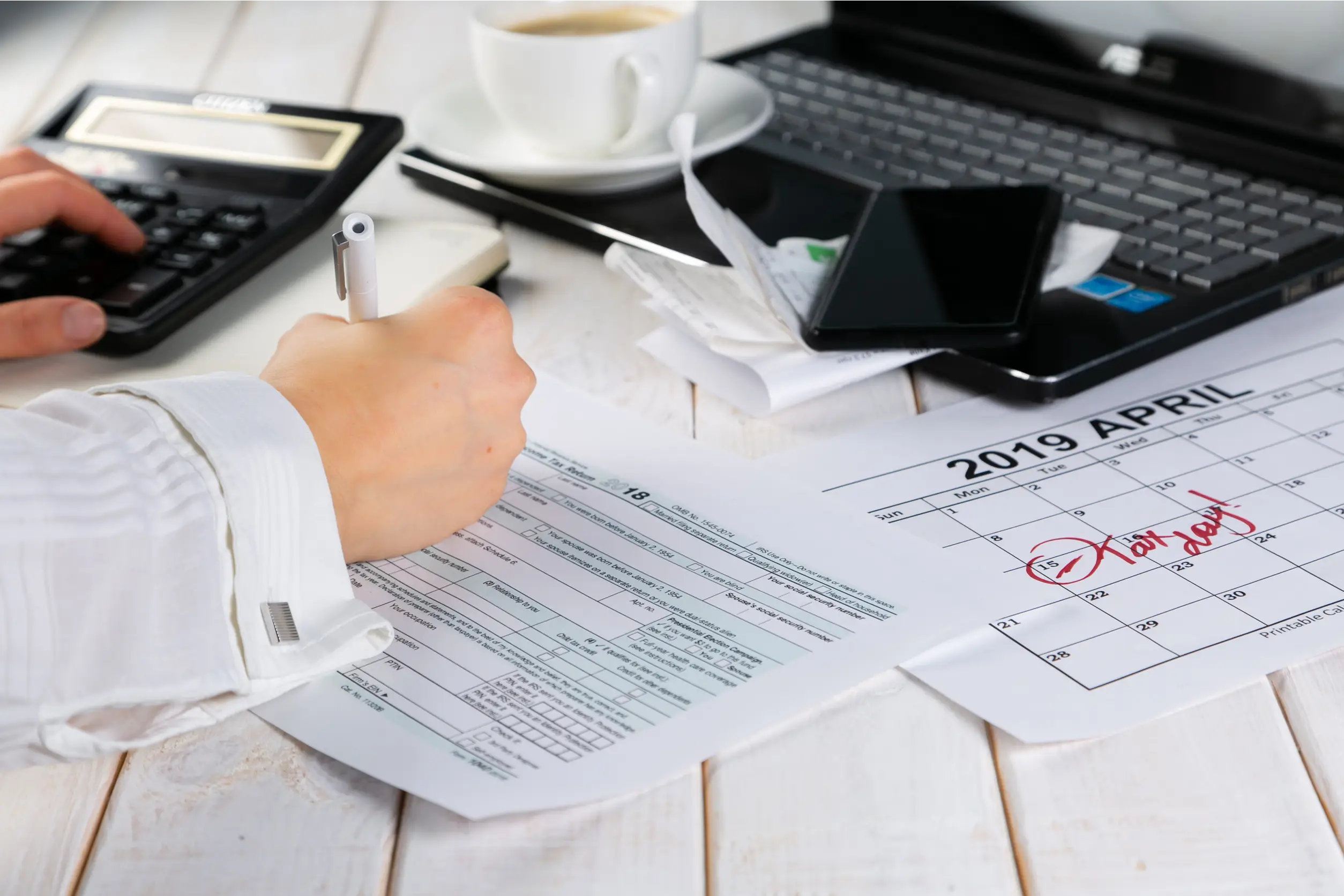 Tax day concept - calculator, calendar, tax form, hands